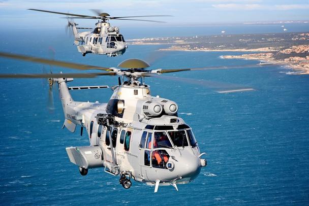 Two Airbus H225M Super Puma helicopters delivered to the Royal Thai Air Force fly in formation over a coastal setting. 