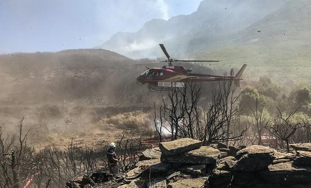 An Airbus-built rotorcraft operated by Mont Blanc Helicoptères supports firefighting efforts, complementing ground crews.