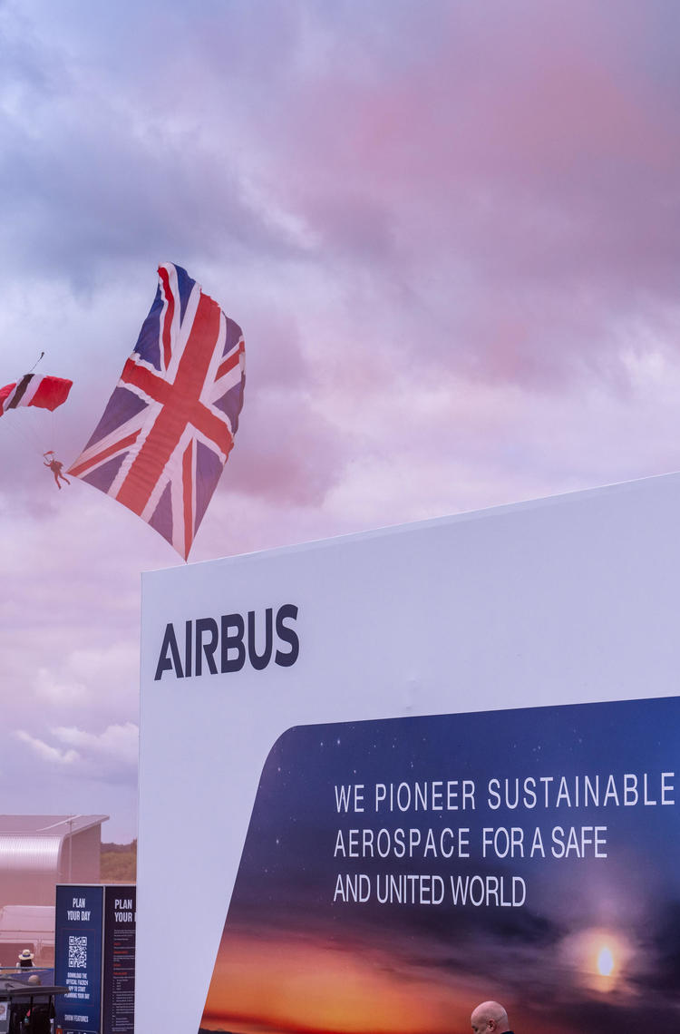 Parachuter with Union Flag in tow drifts to the ground in front of the Airbus pavilion at Farnborough Airshow