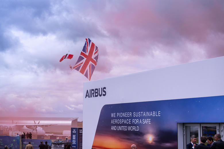 Parachuter with Union Flag in tow drifts to the ground in front of the Airbus pavilion at Farnborough Airshow